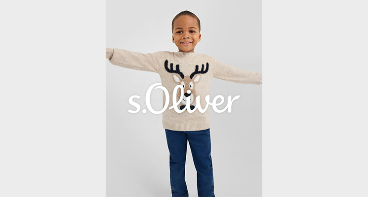 Mädchen mit naturfarbenem Pullover und Elchmotiv sowie blauer Jeans von S Oliver